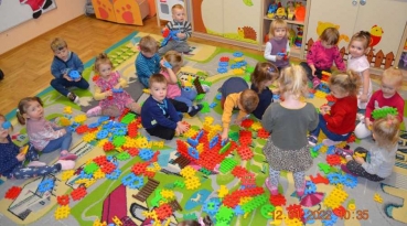 Dzieci bawią się klockami na kolorowym dywanie